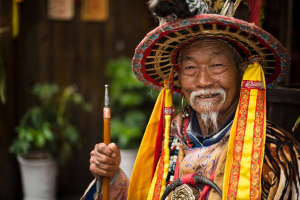 LIJIANG CHINA 2014 مارس 30 یک پیرمرد ملیت نکسو لباس پوشیدن در لباس Dongba باستان لبخند زدن و مسافران خوش آمدید واقع در شهر باستانی لیجینگ استان یوننان چین