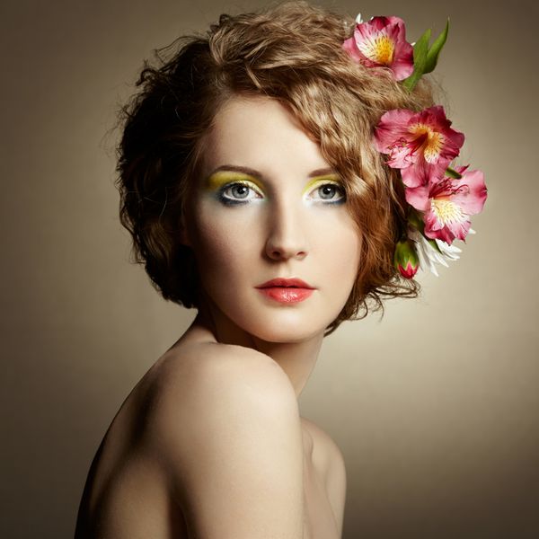 زن جوان زیبا با گل های دلپذیر در موهایشان عکس های بهار