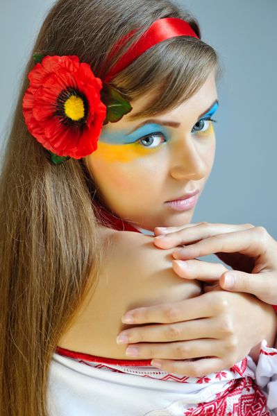 پرتره یک زن با آرایش خلاق پرچم اوکراین در چهره او در لباس ملی اوکراین
