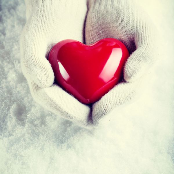 دست زنانه در دستکش های سفید بافتنی با قلب قرمز براق بر روی زمینه ی برف عشق و مفهوم سنت فیلتر نمایش مشخصات عمومی