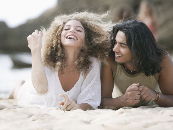 نزدیک یک زن و شوهر جوان دروغ گفتن در ساحل و لبخند زدن