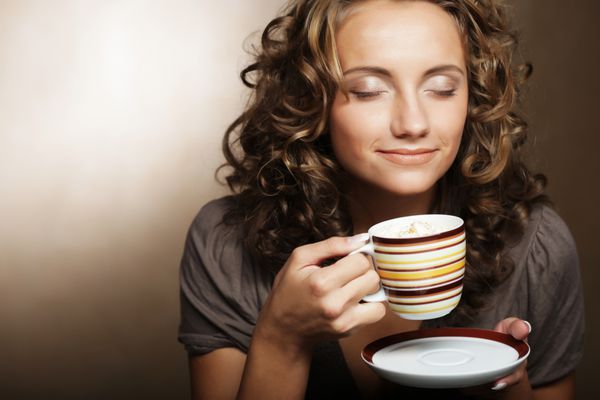 دختر جوان زیبا نوشیدن چای یا قهوه