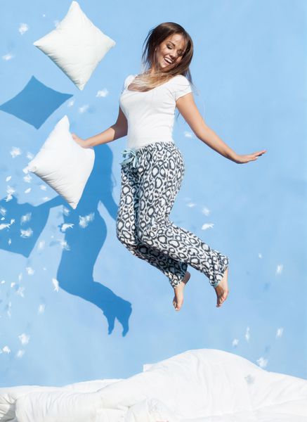 مفهوم مبارک صبح زن داشتن یک بالش پریدن بر روی تخت