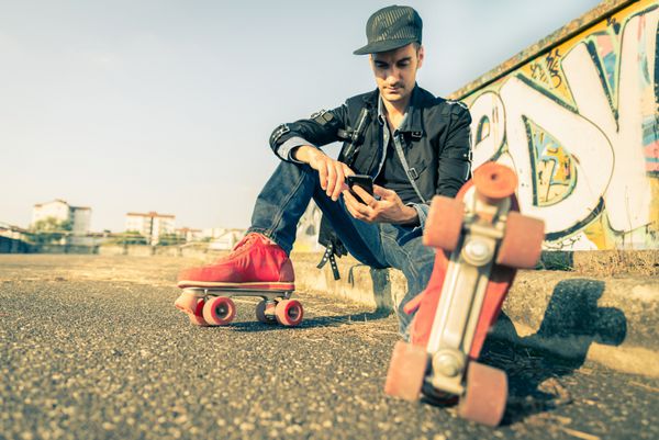 مرد خنک با کفش غلتکی اسکیت با استفاده از تلفن همراه خود مفاهیم جوانان ورزش سبک زندگی و سبک 80 ساله پرنعمت