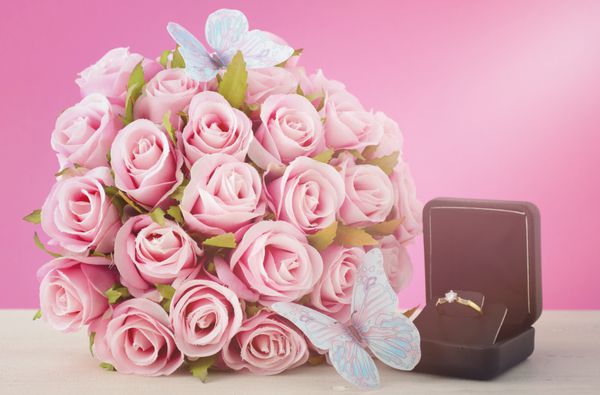 روز عروسی دسته گل رز صورتی و سفید از گلدان های ابریشمی با پروانه های آبی و حلقه عروسی با فیلتر های کاربردی و لامپ ها