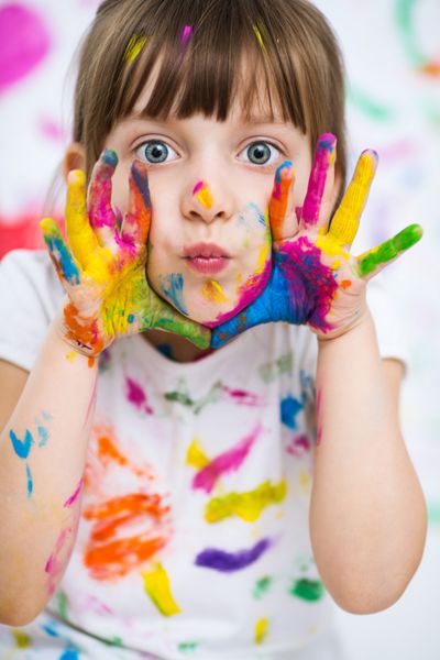 پرتره یک دختر کوچک خوش شاد زیبا نشان دادن دستان خود را در رنگ های روشن رنگ آمیزی شده است