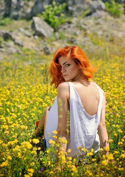 دختر جوان زیبا در میان گل های رنگی زرد