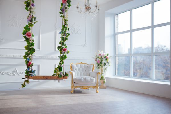 صندلی سبک سبک چرم سفید در اتاق داخلی کلاسیک با پنجره بزرگ و گل های بهار