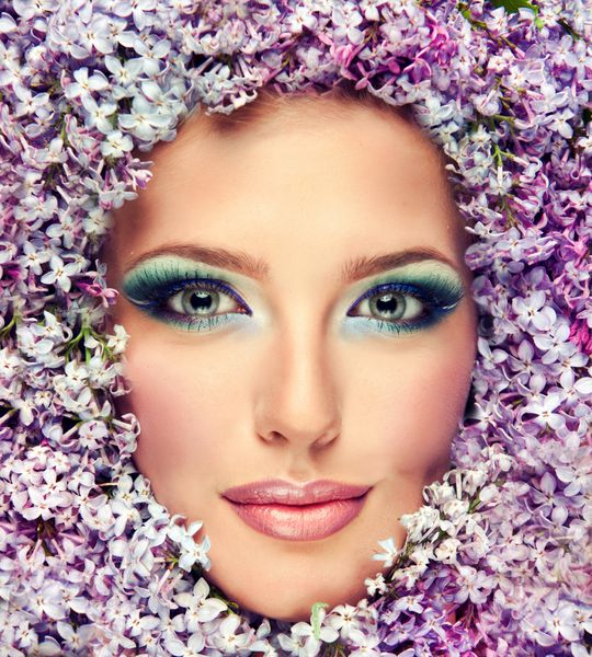 مدل دختر زیبا در گل های یاس بنفش در اطراف صورت تصویر خنده دار از بهار و تابستان تازه آرایش لوازم آرایشی و زیبایی