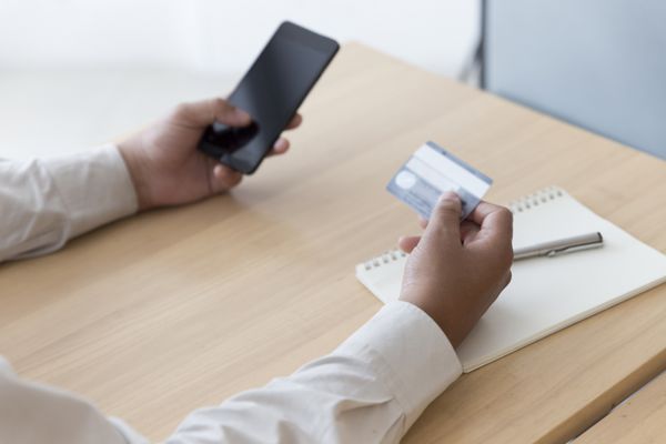 بازرگانان با استفاده از تلفن همراه و کارت اعتباری برای پرداخت مفهوم آنلاین خرید