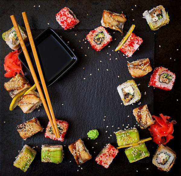 غذا های سنتی ژاپنی سوشی رول و سس روی پس زمینه سیاه مشاهده صفحه