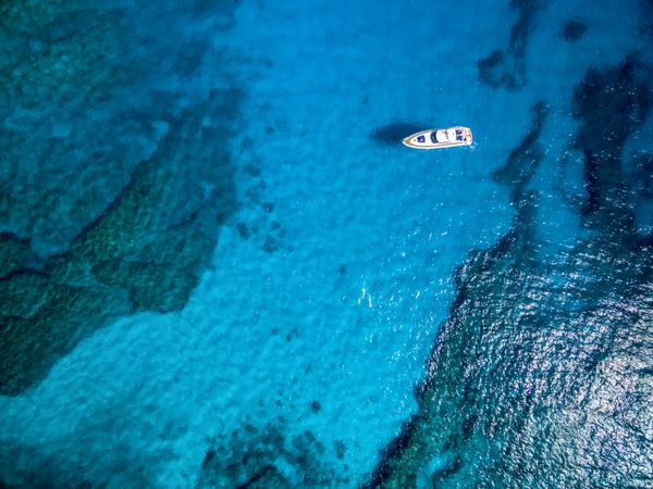 نمای هوایی از تعطیلات ساحل جزیره گرمسیری در صخره های آبی اقیانوس قایق بادبانی