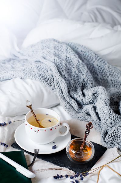 سینی با عسل و یک فنجان چای در بستر صبح تنبل خلق و خوی گرم زمستان