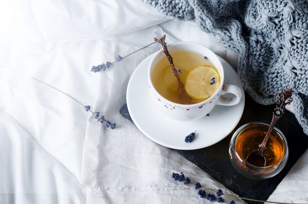 سینی با عسل و یک فنجان چای در بستر صبح تنبل خلق و خوی گرم زمستان