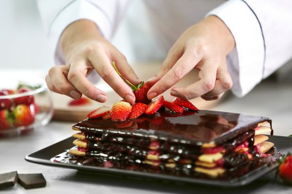 مفهوم پخت و پز شیرینی ساز حرفه ای تزئین کیک خوشمزه با توت فرنگی نزدیک
