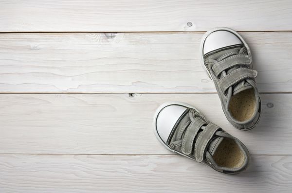 کفش های قدیمی بوش سیاه و سفید یا کفش های ورزشی برای بچه ها یا پای بچه بر روی طبقه چوب سفید و یا جدول بالا با copyspace