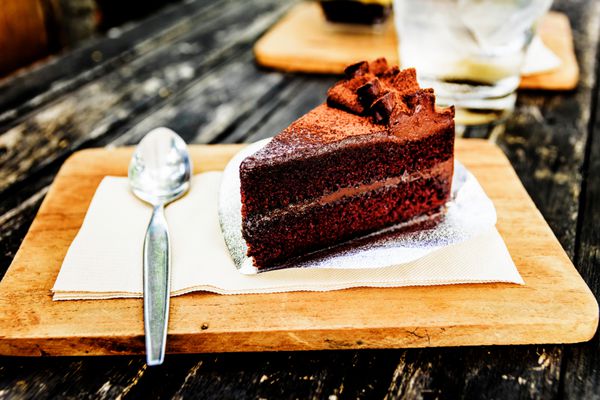 کیک شکلات خوشمزه بر روی صفحه چوبی روی میز چوبی