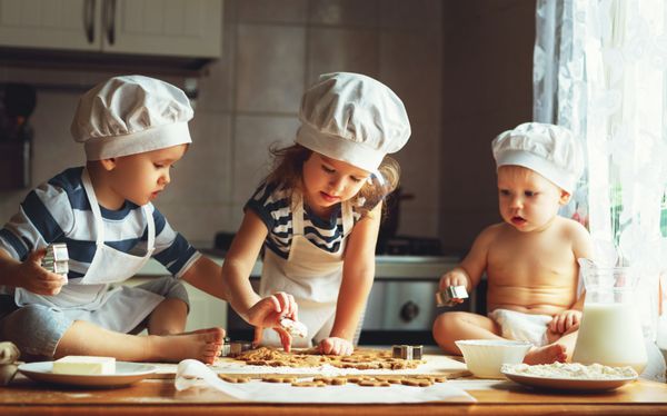 بچه های شاد خانواده خنده دار در حال تهیه خمیر هستند کوکی ها را در آشپزخانه بپزید