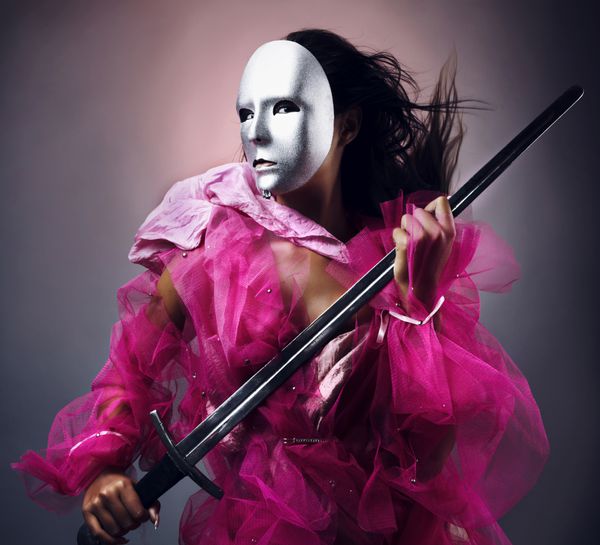 زن جنگجو در یک ماسک نقره ای با شمشیر دست عکس