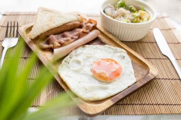 صبحانه آمریکایی تخم مرغ سرخ شده بر روی ظرف چوب با سالاد سبزیجات