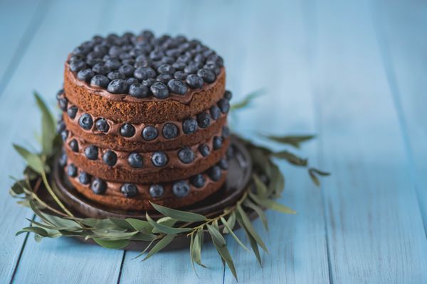 کیک لایه بردار شکلات با زغال اخته با کرم شکلات در یک پس زمینه آبی رنگ در یک صفحه سرامیکی قهوه ای کپی فضای نزدیک