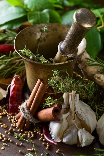گیاهان و ادویه جات مختلف بر روی میز چوبی ملات مس قدیمی با ادویه جات ترشی جات