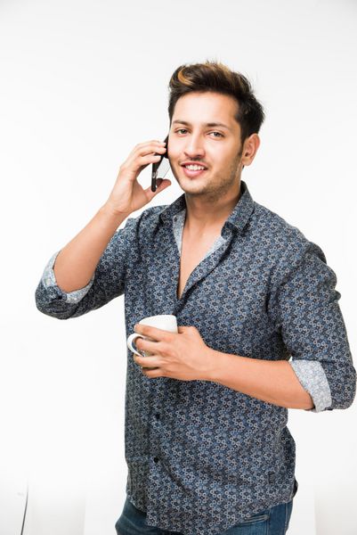 پرتره یک مرد جوان خوش تیپ جوان با یک فنجان قهوه ایستاده جدا شده بر روی زمینه سفید