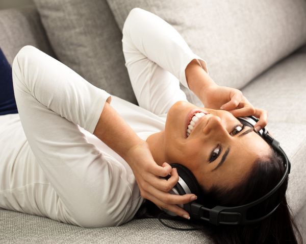 دختر جوان گوش دادن به موسیقی در یک مبل