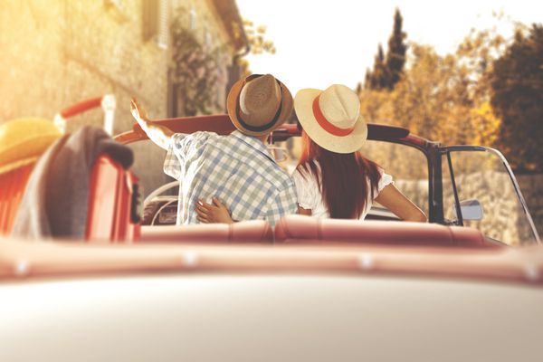 زن و شوهر جوان در ماشین عقب خودرو کابری در غروب خورشید پاییز