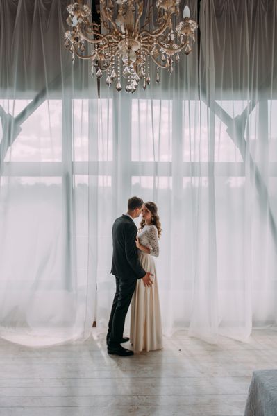 زن و شوهر عروسی ناز در داخل یک استودیو کلاسیک تزئین شده است سلام بوسه و یکدیگر را ببندید