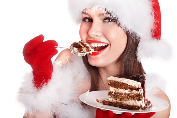 دختر در کلاه سانتا خوردن کیک در صفحه جدا شده