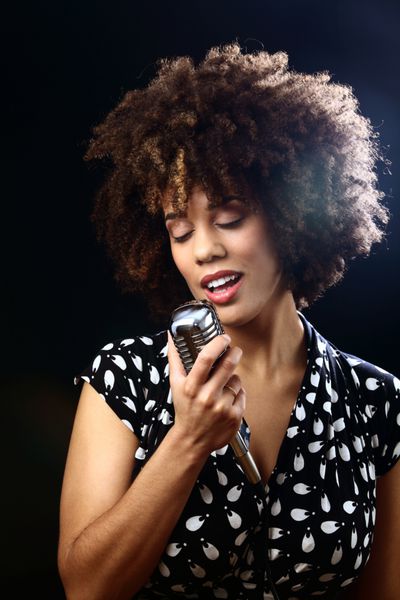 زن جوان برگزاری یک میکروفون یکپارچهسازی با سیستمعامل و آواز خواندن