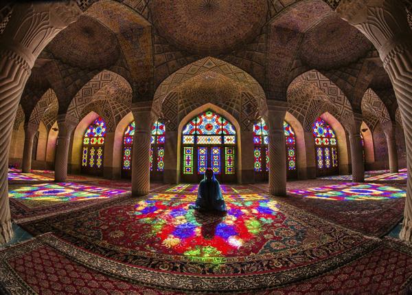 بانوی ایرانی نشسته در نورهای تابیده شده از معماری ایرانی