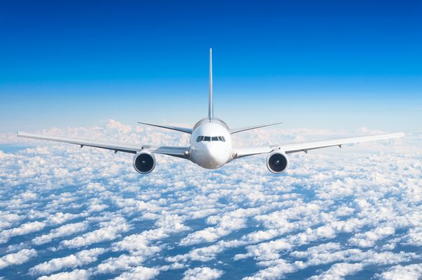 هواپیمای مسافربری که در سطح پرواز بالا در آسمان بالاتر از ابرها و آسمان آبی پرواز می کند دقیقاً در جلو دقیقاً مشاهده کنید