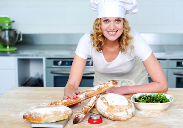 زن نانوایی که غذای سالم تهیه می کند به دوربین نگاه می کند و لبخند می زند