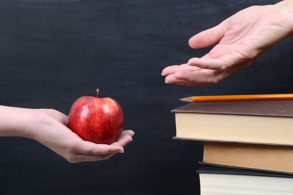 دانش آموز با دادن یک سیب به معلم