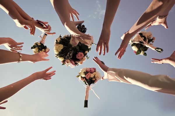 دستان زنان amp amp؛ x27؛ سعی در گرفتن چهار دسته عروس زیبا از گل رز پاستیل در پس زمینه روشن آسمان آبی عکس افقی