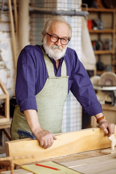 پیرمرد در عینک و لباس های گاه به گاه دوست دارد با چوب کار کند پیرمرد در نجاری خوب است