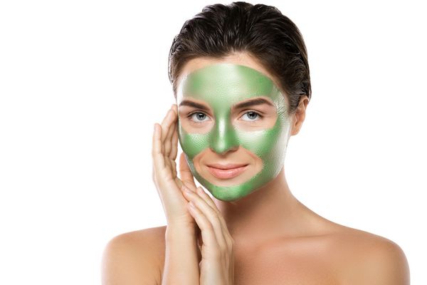 زن با ماسک پوست کنده سبز بر روی صورت خود که در زمینه سفید جدا شده است