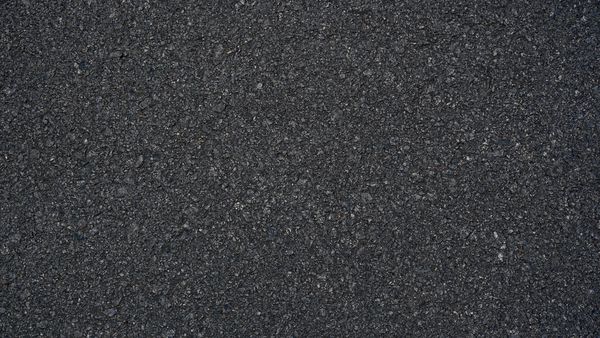 سطح ناهموار سطح آسفالت جاده دانه ای خاکستری تیره بدون درز پس زمینه بافت نمای بالا