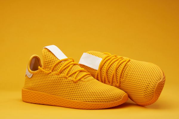 کفش های مدرن تنیس زرد جدا شده در زمینه نارنجی