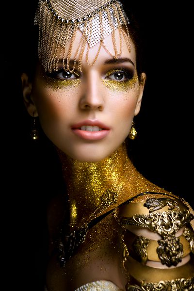 پرتره زن زیبا با جرقه های طلایی روی صورتش دختری با آرایش هنری با جرقه های طلایی مدل مد با آرایش طلایی