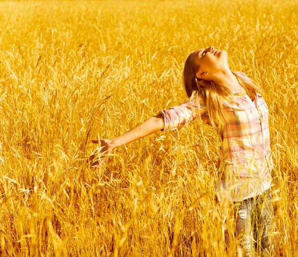 عکس نوجوان شاد و سرگرم کننده در حومه شهر دختر شاد ناز ایستاده در مزرعه گندم با دستهای بلند و نگاه کردن به بالا دختر با لذت از طبیعت پاییز فصل پاییز