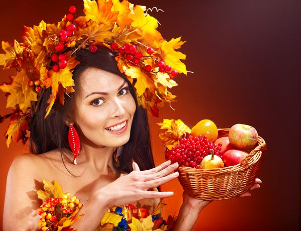 دختری با تاج گل پاییز برگ سبد میوه را نگه می دارد
