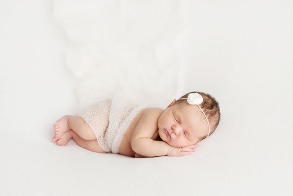 خوابیدن دختر تازه متولد شده بر روی زمینه سفید فتوشاپ برای نوزاد 7 روز از بدو تولد پرتره دختر بچه ای زیبا و هفت روزه و تازه متولد شده