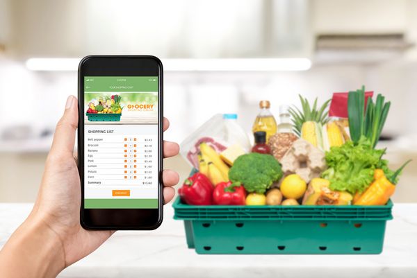 فروشگاه خرید مواد غذایی آنلاین در صفحه گوشی های هوشمند با مواد غذایی در خانه در پس زمینه
