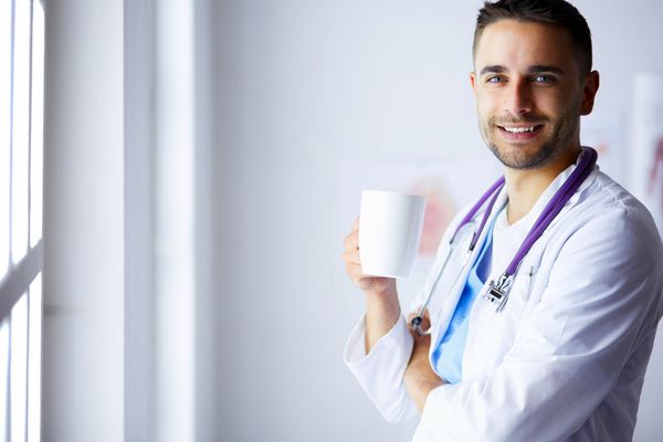 پزشک جوان با فنجان قهوه در مطب