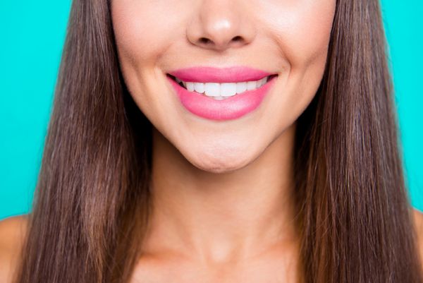 نزدیک عکس پرتره عکس زن زیبا و زیبا بسیار جذاب با ایده های کامل دندان شنی دندان کامل و مستقر در زمینه روشن روشن آبی