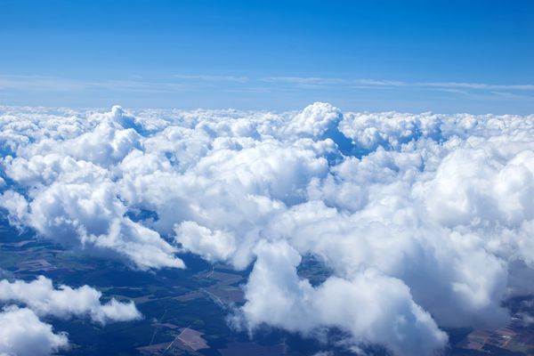 نمای زیبا از ابرهای کومولوس با اتمسفر روز آفتابی از پنجره هواپیما