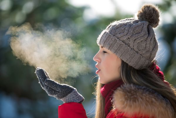 زن جوان جذاب در زمستان بخار بیرون از هوا تنفس می کند